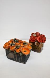 Szkliwione kwiaty ceramiczne w kolorach czerwonych i pomarańczowych.