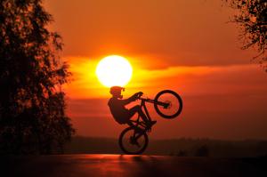 Rowerzysta wykonuje ewolucje w świetle zachodzącego słońca