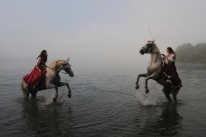 Dwie kobiety na koniach, w wodzie, wykonują ewolucje