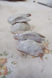 Na zdjęciu dwa zające z gliny, szkliwione na biało