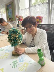 Uczestniczka przy biurku z drzewkiem wykonanym z kawałków materiału.